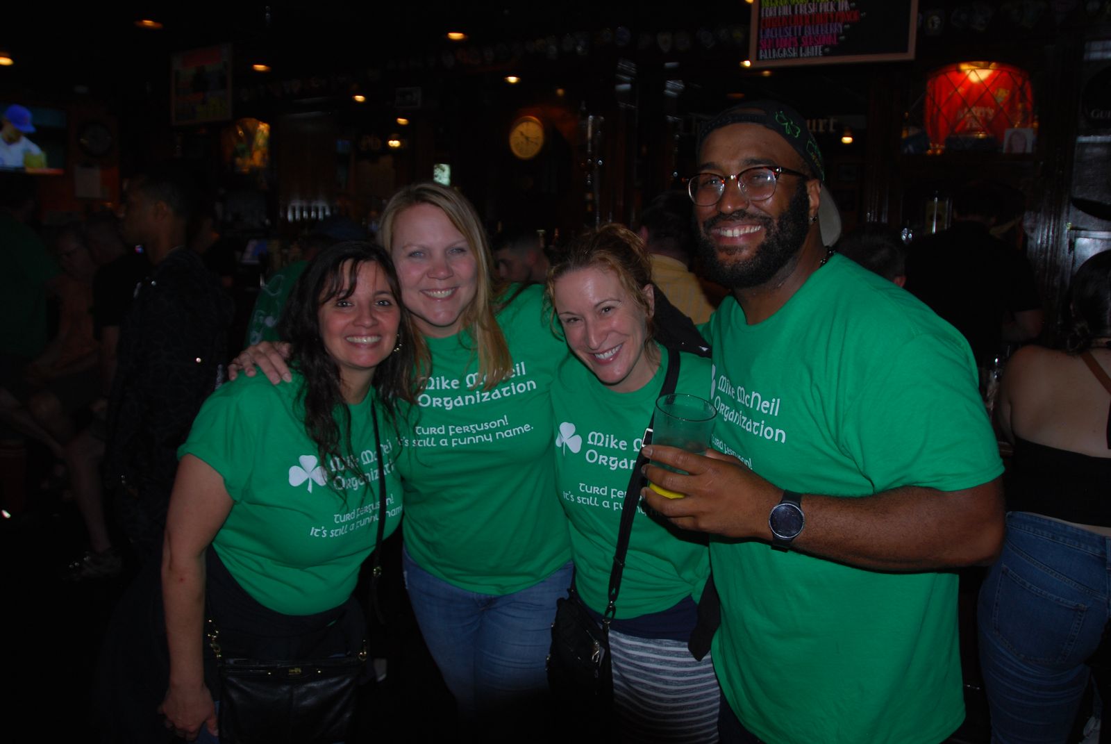 Four friends in green Mike McNeill Organization shirts smiling at a past Crawl for a Cure